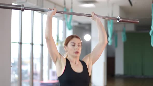 A woman lifts a barbell in the gym, a fitness woman does strength exercises