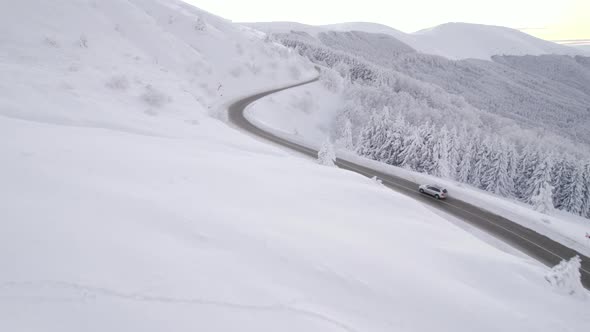 Drone Follows Silver SUV Speeding Uphill on Steep Mountain Road in Winter Conditions