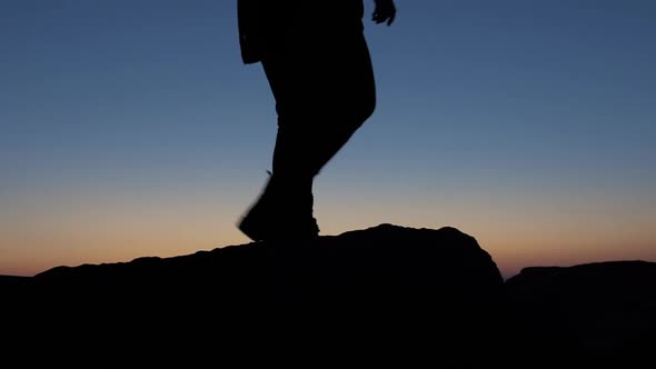 A silhoutte of a girl walking on rocks during blue hour. Slow motion.