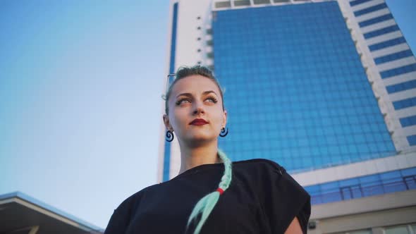 Portrait of Young Stylish Funky Hipster Woman with Green Hair on Urban Buildings Backgorund Slow