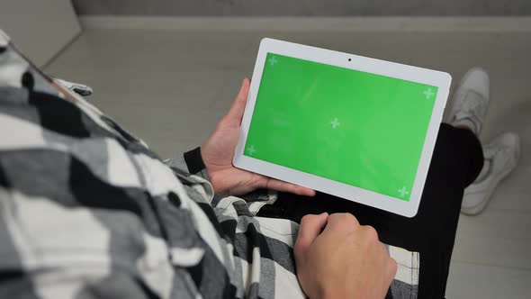 Man Sitting on Chair Looking at Digital Tablet with Green Screen Chroma Key