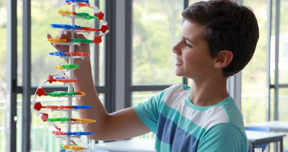 Attentive schoolboy experimenting molecule model in laboratory