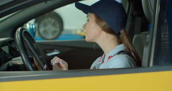 Female Mechanic Sitting in Car Doing Diagnostics on Digital Tablet.