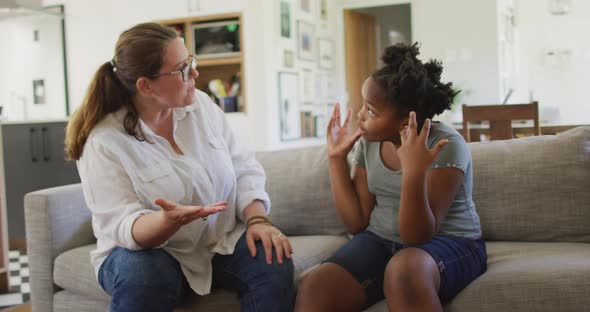 Caucasian woman arguing with her african american daughter in living room