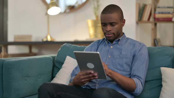 Young African Man Using Tablet on Sofa