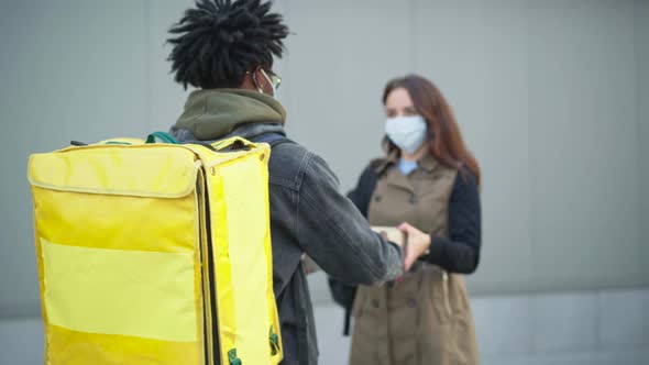 Rack Focus Goes From African American Male Courier To Caucasian Woman in Covid19 Face Mask Receiving