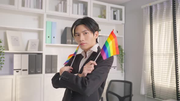 Portrait of Asian businessman gay working in office, holding LGBT flag.