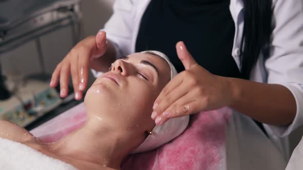 Closeup View of a Professional Cosmetologist's Hands Making Face and Neck Massage in Spa Salon