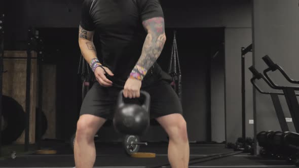 Fitness Man Training at the Gym Using Kettlebell Weights and Squat Strength Exercise