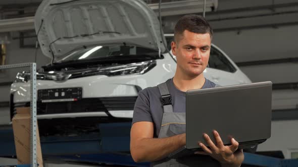 Car Mechanic Smiling Showing Thumbs Up While Working on the Laptop