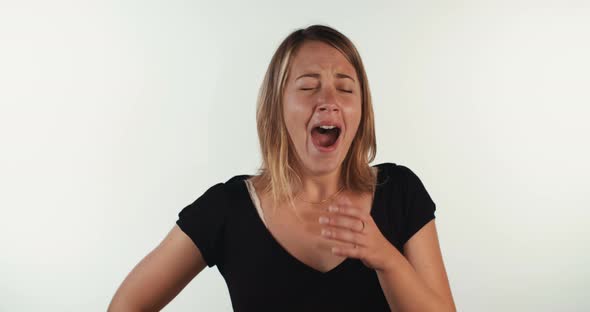 Young blond woman yawning in slow motion on white background