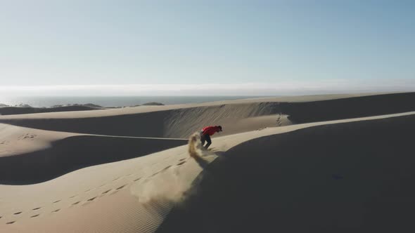 Man Energetically Running Up Dunes Creating Golden Clouds of Sands at Sunset