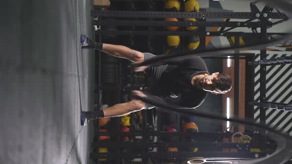 Strong Young Man Working Out with Battle Ropes at Crossfit Gym