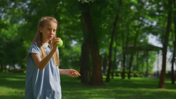 Girl Training to Throw Ball in Green Park Close Up