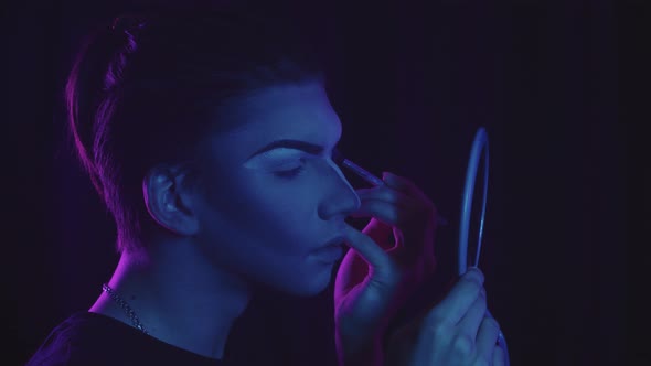 Drag Artist  Young Man Applying Light Concealer Under His New Drawn Eyebrows  Neon Lighting