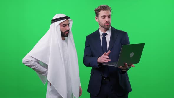 Businessman in Uses a Laptop and Communicate with a Arab Business Partner in a White Kandura