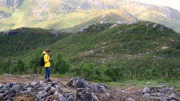 Young Woman Traveler Standing on a Mountain and Using Her Smartphone