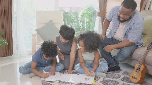 Happiness family with father and mother looking children drawing with colorful pencils.