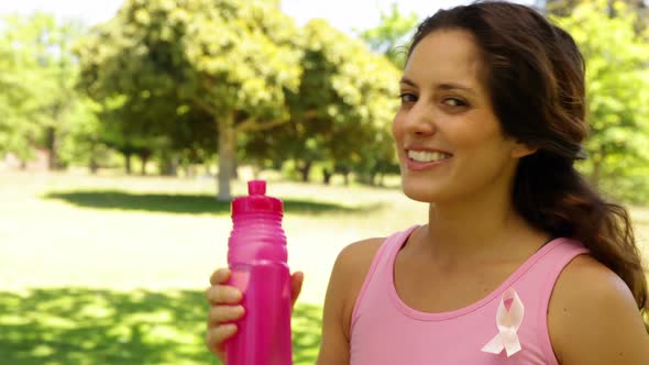 Happy woman wearing pink for breast cancer awareness drinking water