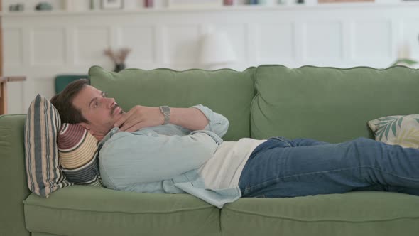 Pensive Young Man Thinking While Lying on Sofa