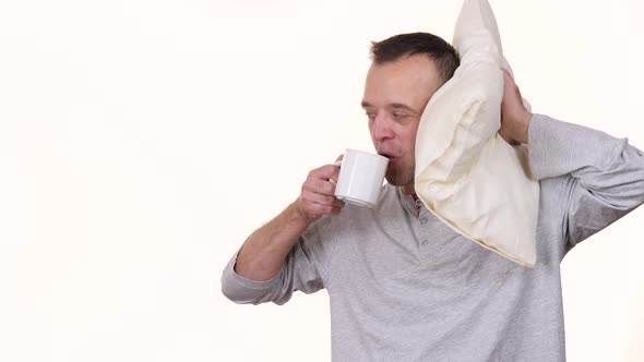 Man Tired at Morning Holds Coffee Mug and Pillow