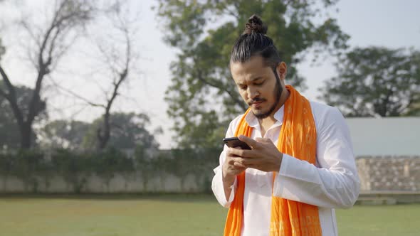 Indian man using smartphone in a traditional Indian outfit