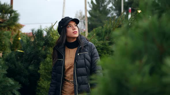 A woman shopping for holiday decorations on a Christmas tree farm lot.