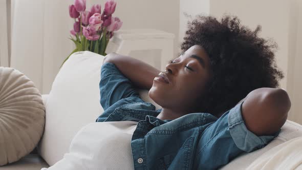 Healthy Tired Serene African American Young Woman Leaning on Comfortable Sofa Does Neck Massage