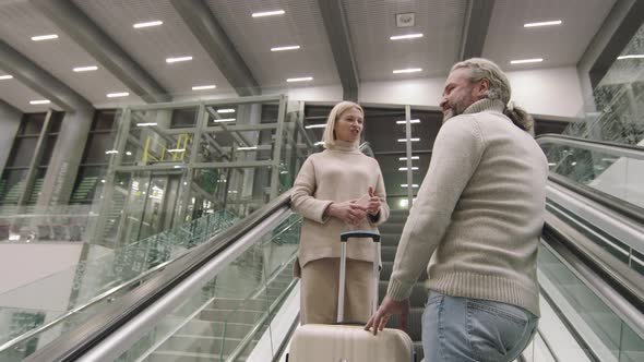 Couple With Suitcases On Escalator