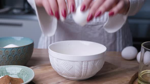 Woman's Hand Cracking White Eggs Into Bowl For Baking Carrot Cake. - close up