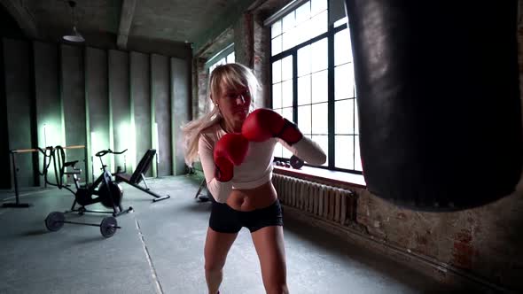 Blonde Female Boxer Fighting with a Punching Bag in the Gym. Healthy Lifestyle, Sports.