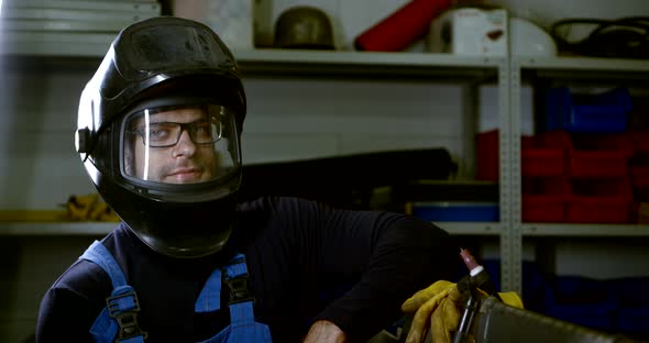 Close-up Portrait of a Welder Man in Glasses, Gloves and a Helmet Looking and Smiling.