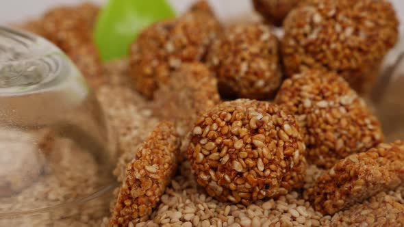 Close view of sesame seeds ladoo and sticks  placed over heap of sesame seeds