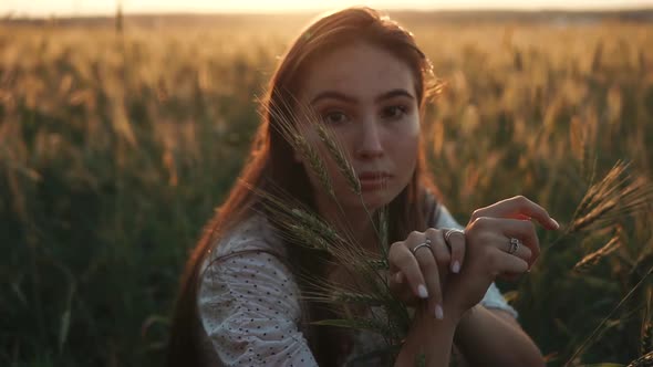 Charming Young Brunette Girl Is Sitting Alone in Field of Ripened Wheat in Fall