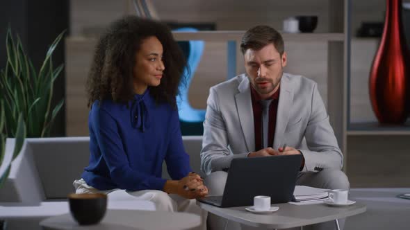 Creative Multiracial Business Couple Working Together Researching Laptop in Cafe