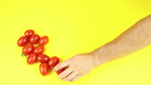 Hand Rests Tomatoes on Yellow Table