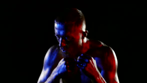 a Muscular Man with a Bare Torso and Golden Metallic Skin is Boxing Against a Dark Background