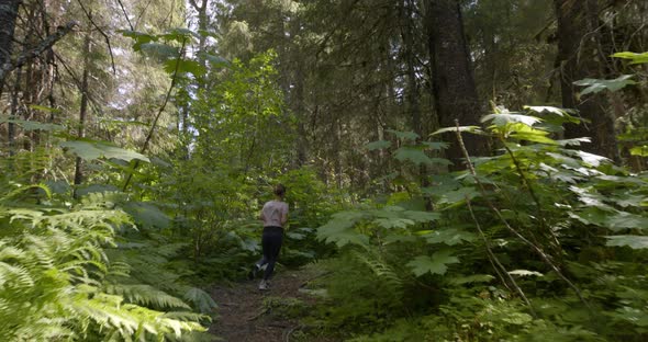 Active Female Jogger Inside The Forest Park Enjoying Her Morning Run Through Sunny Day In Alaska. -