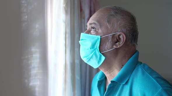 Senior Man with Face Mask Looking Through Window.