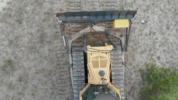 Top Aerial View on Tracked Bulldozer Rides on Sandy Road at Construction Site