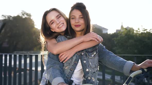 Girlfriends Sitting on Bike and Posing on Camera with Cute Smiles on the Sunset