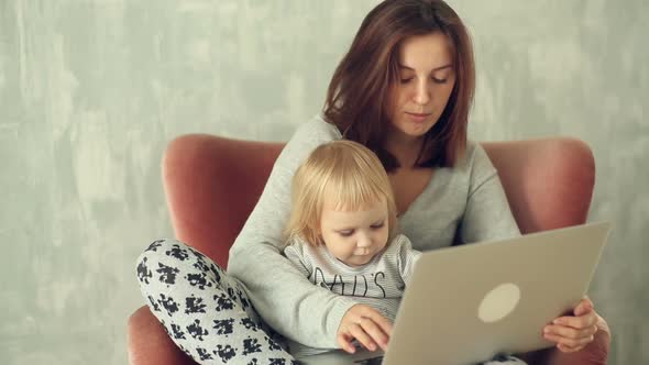 Beautiful mother with little daughter using laptop