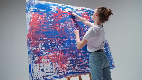 Young Woman Artist Draws with Her Hands on a Large Canvas in a White Room a Talented Artist Draws a
