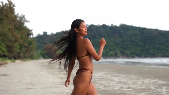 Beautiful Young Woman Walking Along Beach In Bikini