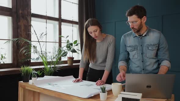 Young Woman and Man As an Architects Working with Blueprints, Laptop and House Models in the Office.