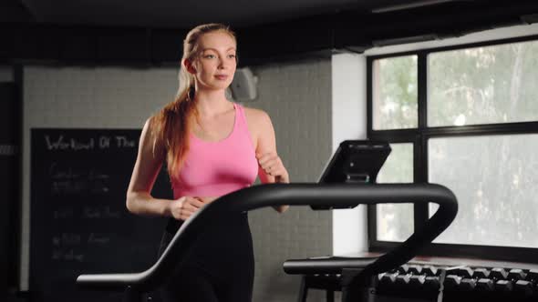 Woman athlete running on treadmill, doing cardio workout in gym