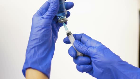 Health Worker Dials the Vaccine From Ampoule Into a Syringe Wearing Blue Protective Gloves
