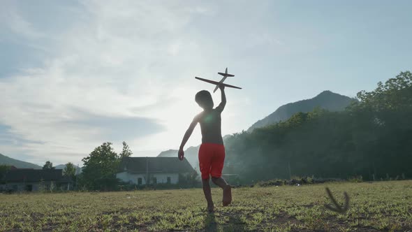 Rural Boy Playing A Cardboard Airplane With Sun