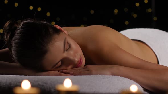 Girl Resting in Room with Burning Candles and Dark Background