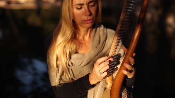 Sensual female musician playing lyre in garden